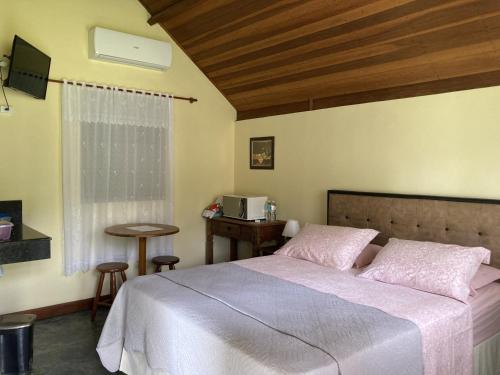 库尼亚Pousada Colar de Ouro Chalés的一间卧室配有一张床、一张桌子和一个窗户。