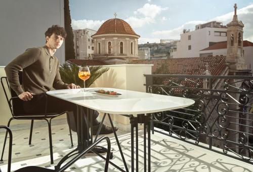 雅典Monument的坐在阳台上桌子上的人,喝一杯葡萄酒