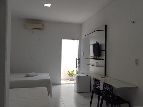 圣阿马鲁Ville Portal das Dunas Suites - St Amaro的白色的客房配有床、书桌和电视。