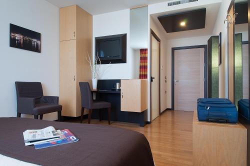 赛拉诺三鹿酒店的酒店客房配有一张床、一张书桌和一台电视。