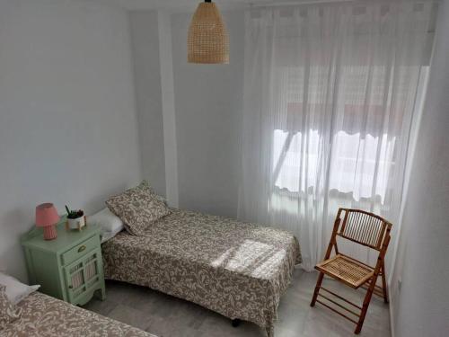 萨各夫雷纳Apartamento con vistas al mar.的一间卧室设有两张床、一把椅子和一个窗户。