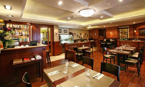 布达佩斯布达佩斯黄金酒店的一间带桌椅的餐厅和一间酒吧
