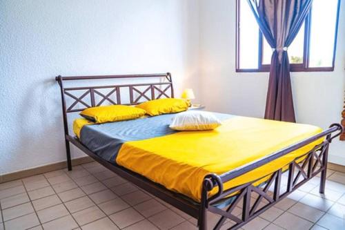 库鲁Bel appartement T2 * Netflix * Terrasse* Parking的一间卧室配有一张带黄色床单的床和一扇窗户。
