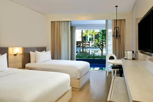 库塔The Stones Hotel - Legian Bali, Autograph Collection的酒店客房设有两张床和电视。