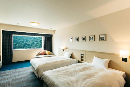 别府KAMENOI HOTEL Beppu的酒店客房设有两张床和窗户。