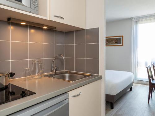 阿维尼翁Appart'Hotel - Gare TGV - Courtine - Confluence - 218的一个带水槽的厨房和一张位于客房内的床