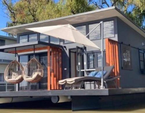 White SandsArk-imedes - Unique float home on the Murray River的一个小房子,有门廊和雨伞