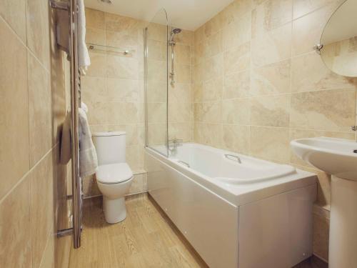 圣马丁格恩西女王宾馆的浴室配有卫生间、盥洗盆和浴缸。