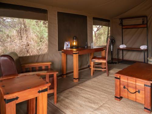 安博塞利Tulia Amboseli Safari Camp的客房设有桌子、椅子和书桌。