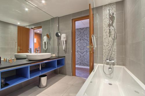 巴黎TRYP巴黎布兰驰枫丹酒店的浴室配有2个盥洗盆、浴缸和淋浴。