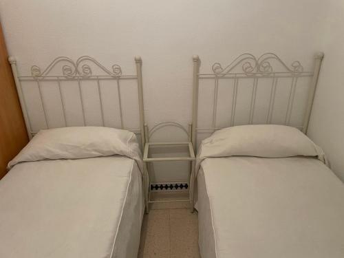 克莉丝蒂娜岛Piso Isla Cristina Punta del Caimán的两张睡床彼此相邻,位于一个房间里