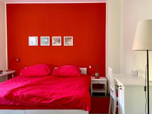 莱比锡die Senfbude - schöne, ebenerdige 2-Raum-Apartments mit Stellplatz und Terrasse的红色的卧室,配有一张红色墙壁的床