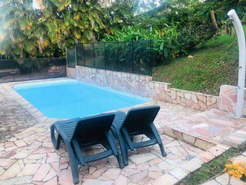 Saint-JosephCharmant bungalow avec piscine的游泳池旁设有两把椅子和一张桌子