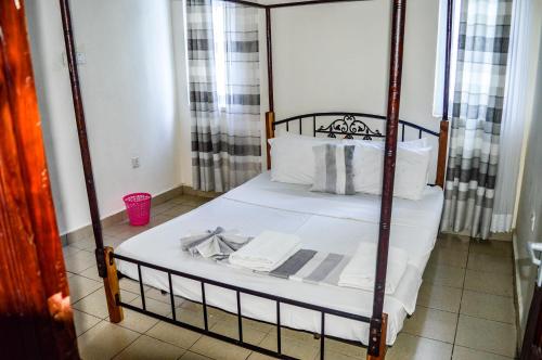 蒙巴萨Roma Stays Mwtapa Luxury Apartments 3 bedrooms & swimming pool的一间卧室配有一张带白色床单的四柱床