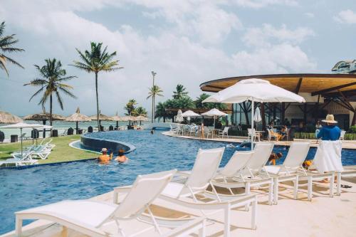 María ChiquitaAmazINN Places Playa Escondida SeaView的度假村的游泳池,配有白色椅子和水中的人