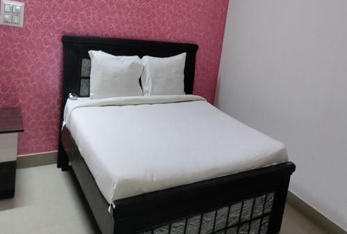 希莫加STAYMAKER Anjaneya Comforts的卧室配有白色床和粉红色墙壁