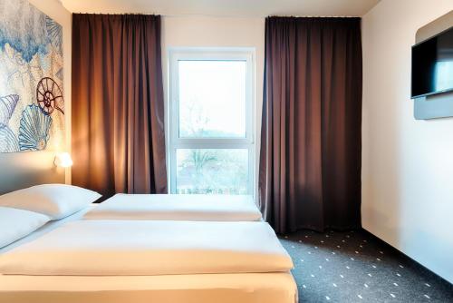 埃姆登B&B Hotel Emden的配有窗户的酒店客房内的两张床