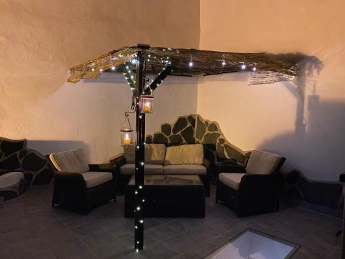 圣巴托洛梅Casa Rural in Fataga的客厅配有沙发和遮阳伞下的椅子