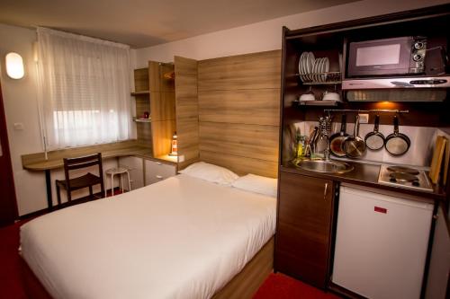 拉克雷奇索罗尼奥尔A83旅馆的一间小卧室,配有白色的床和一间厨房