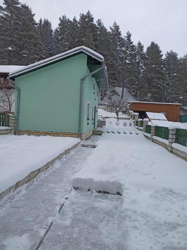 上鲁日巴希Ubytovanie v súkromí Zelený dom的一座有雪盖的院子,后面有一座建筑