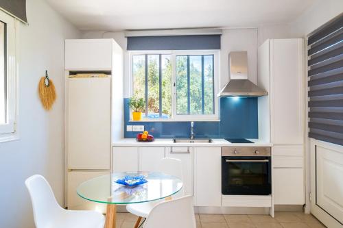 干尼亚Coco Studio的厨房配有玻璃桌和白色橱柜