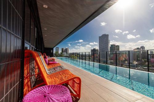 累西腓TOLIVE One Housi Recife by Carpediem的大楼内带长椅和游泳池的阳台