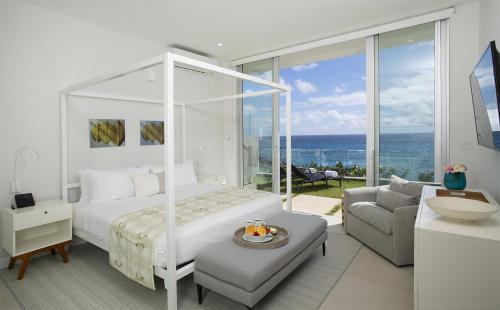 百慕大Azura Bermuda的一间卧室配有一张床,客厅享有美景。
