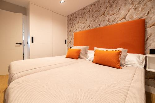 布埃乌Apartamento Illa do Santo的一间卧室配有一张带橙色床头板的大床