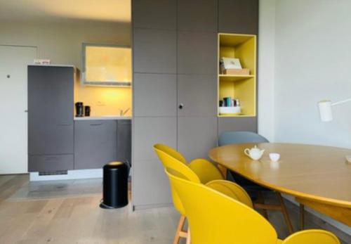 BazelBAZ holiday homes的一间带桌子和黄色椅子的用餐室