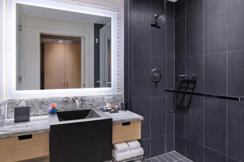 萨拉索塔Art Ovation Hotel, Autograph Collection的浴室配有盥洗盆和带镜子的淋浴