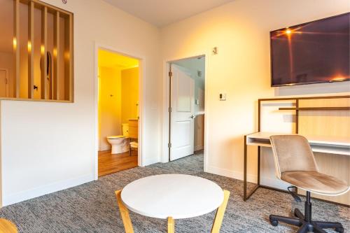 罗利TownePlace Suites by Marriott Raleigh - University Area的客房设有书桌、桌子和椅子。