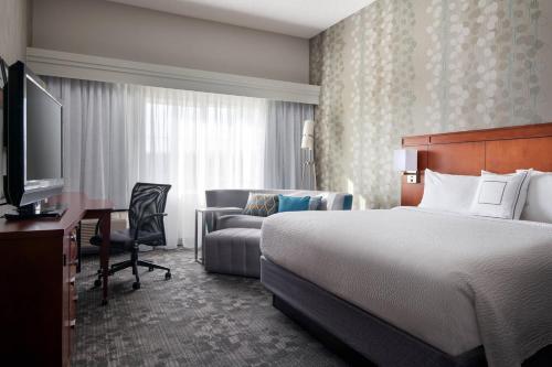 米尔皮塔斯米尔皮塔斯硅谷万怡酒店的酒店客房配有一张床、一张书桌和一张沙发。