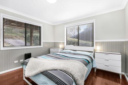 卢拉Baileys Retreat的一间卧室设有一张床和两个窗户。