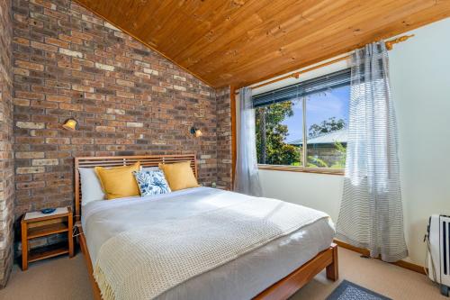 WoodfordGrey Gum Lodge的砖墙房间的一个床位
