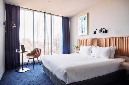 EppingMantra Melbourne Epping的配有一张床、一张书桌和一扇窗户的酒店客房