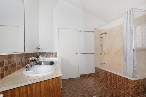 穆德吉巴24 Sundew Street的浴室配有水槽、淋浴和浴缸。
