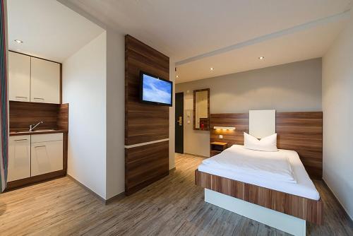 慕尼黑慕尼黑阿帕特中心酒店的一间卧室配有一张床,墙上配有电视