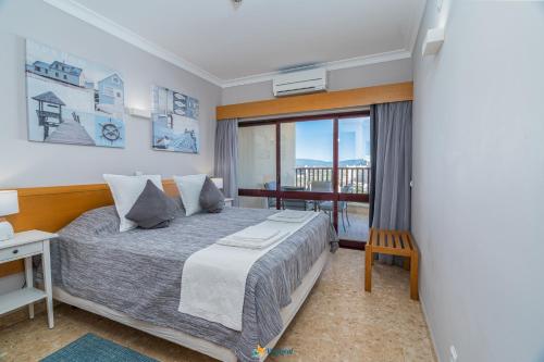 波尔蒂芒Praia Mar - Apartamento Viva Local的一间卧室设有一张大床和一个窗户。