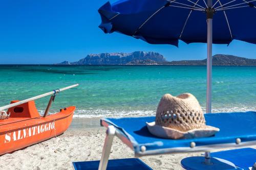 奥尔比亚斯特法尼亚海滩边酒店的坐在海滩上的草帽,有船
