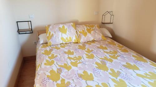 苏安塞斯La Casuca de Rosi en Suances的一张带粉红色和黄色棉被和枕头的床