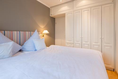 诺德奈Inseldomizil Whg 03的卧室配有带蓝色枕头的大型白色床