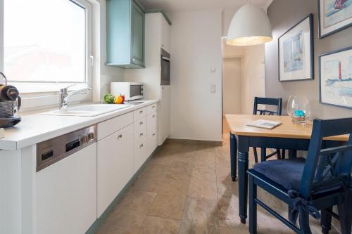 诺德奈Inseldomizil Whg 03的厨房配有白色橱柜、桌子和窗户。