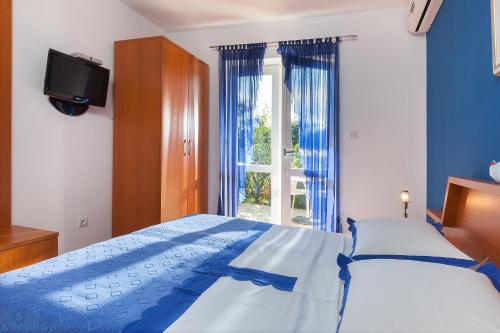 马卡尔斯卡粉红别墅酒店的一间卧室设有一张床、一台电视和一个窗口。