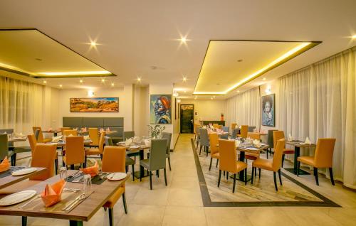 坎帕拉Source of the Nile Hotel - Namanve的一间在房间内配有桌椅的餐厅