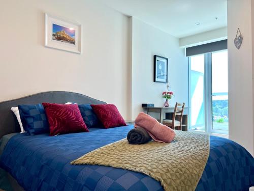 墨尔本Sweet Home Apartment North Melbourne的一间卧室配有蓝色的床和红色和蓝色枕头