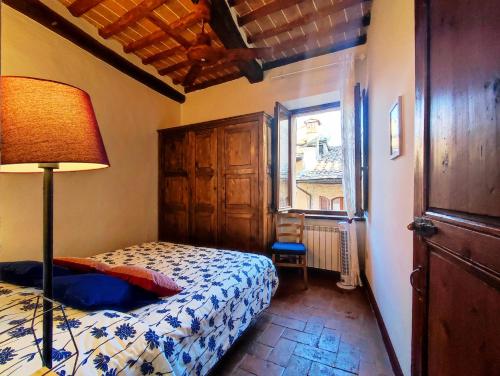 圣吉米纳诺Convento San Gimignano Apartments的一间卧室配有床、灯和窗户