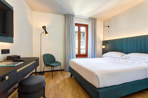 卢加诺LUGANODANTE - We like you的酒店客房,配有一张床、一张桌子和椅子