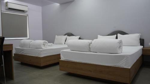 贾姆谢德布尔POD N BEYOND SMART HOTEL @BISTUPUR的客房内的两张床和白色枕头