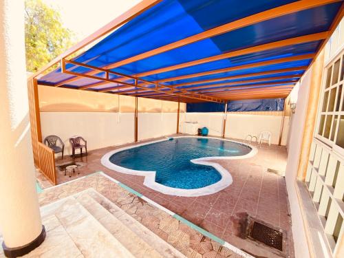 沙迦Holiday Home Rent villa的蓝色遮阳篷房子中的游泳池