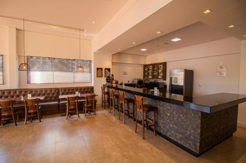 安帕鲁Prado Hotel的餐厅设有酒吧,配有木凳